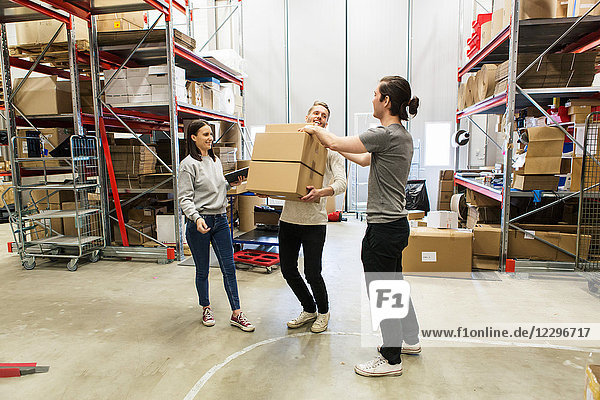 Coworkers assisting man in carrying boxes at distribution warehouse