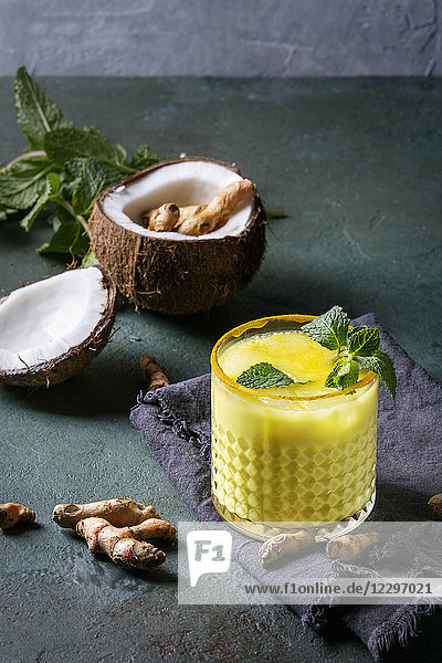 Glas ayurvedisches Getränk Golden Coconut Milk Curmeric Iced Latte mit Kurkumapulver  Minze und Zutaten
