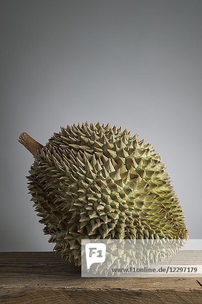 Eine Durianfrucht vor einem grauen Hintergrund