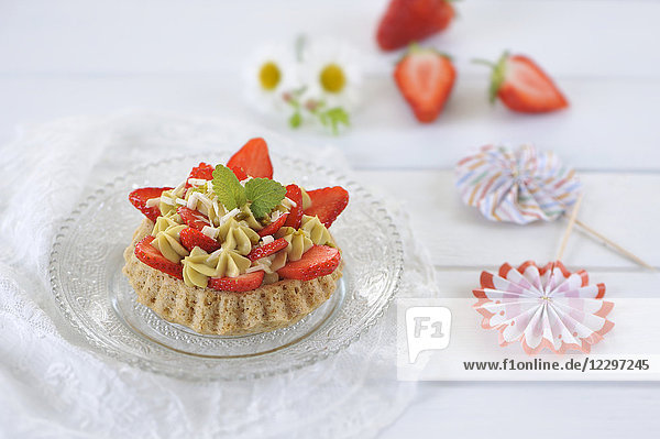 Erdbeertorte mit Mandelkeksen und Pistaziencreme  dekoriert mit frischen Erdbeeren und weißer Schokolade (vegan)
