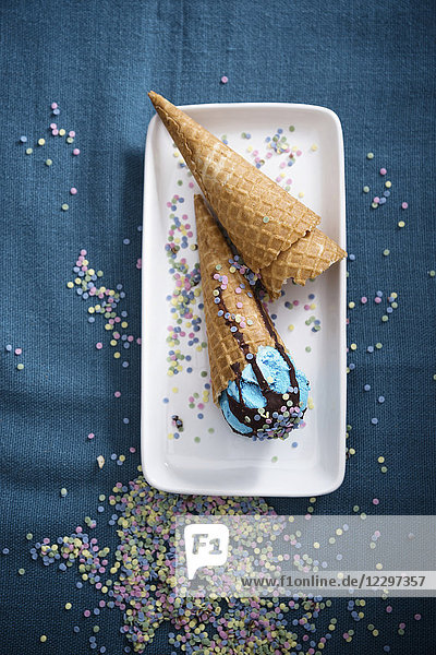 Veganes blaues Eis mit Schokosauce und Zuckerkonfetti in Waffeltüte