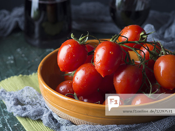 Rohe Tomaten in einer rustikalen Schüssel auf dunklem Hintergrund