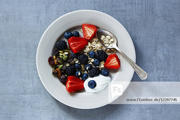 Haferflocken  Beeren mit Joghurt und Samen zum Frühstück auf einem Teller über grauem Vintage-Hintergrund