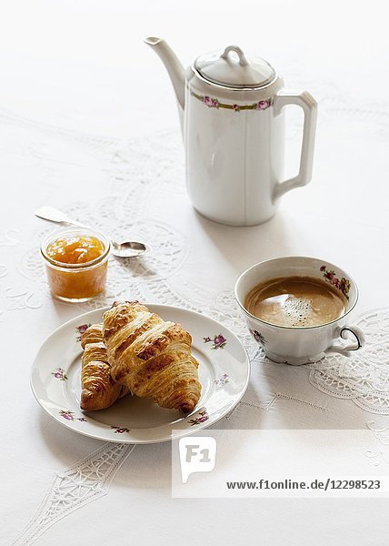 Croissants  ein Glas Aprikosenmarmelade  eine Tasse Kaffee und ein Kännchen Kaffee