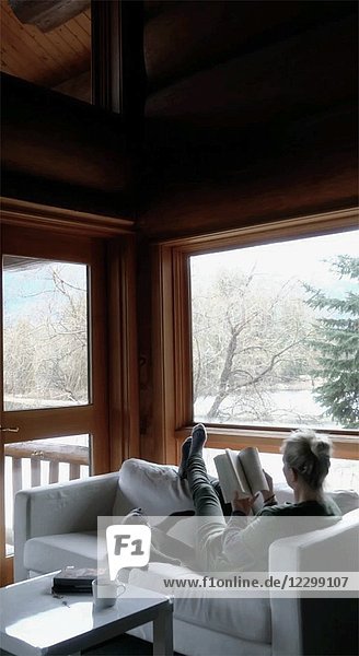 Entspannte Frau liest Buch auf Sofa