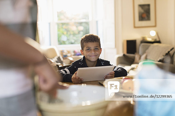 Portrait smiling boy using digital tablet in kitchen