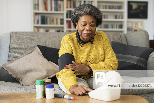 Senior woman checking blood pressure in living room