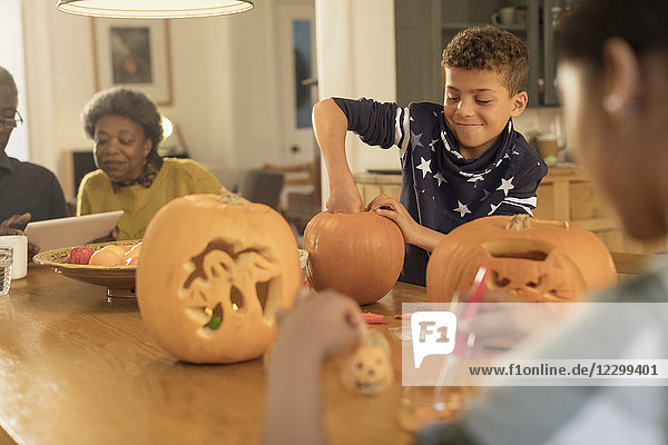 Boy carving Halloween pumpkins at table