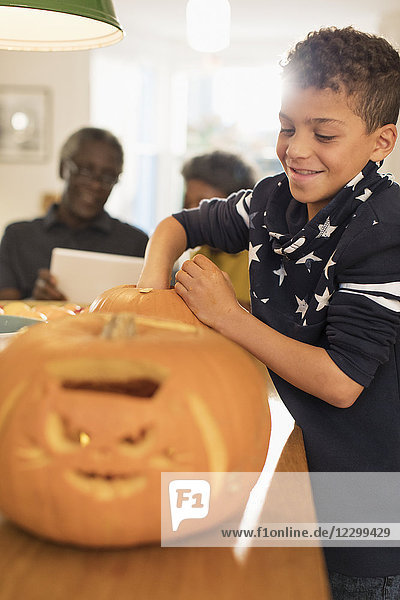Smiling boy carving Halloween pumpkins