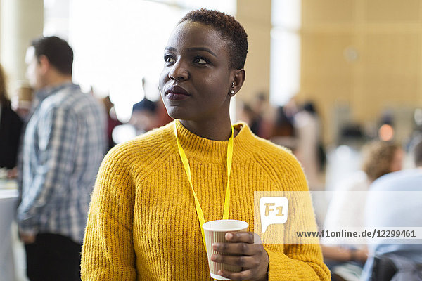 Thoughtful businesswoman drinking coffee at conference