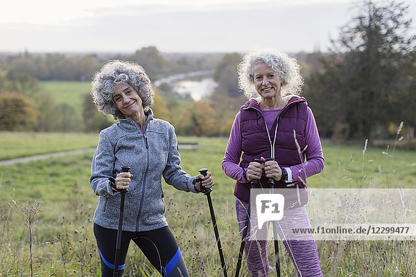Portrait confident active senior women hikers with poles in rural field