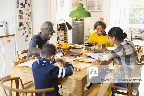 Grandparents at dining table with grandchildren doing homework