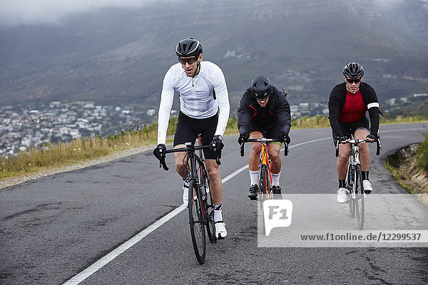Dedicated male cyclists cycling on uphill road