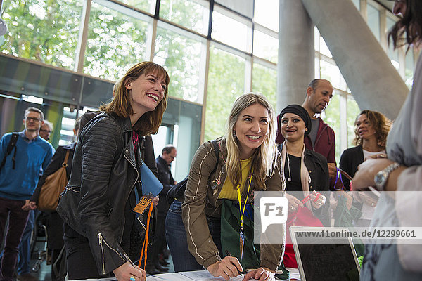 Smiling businesswomen arriving  checking in at conference registration table