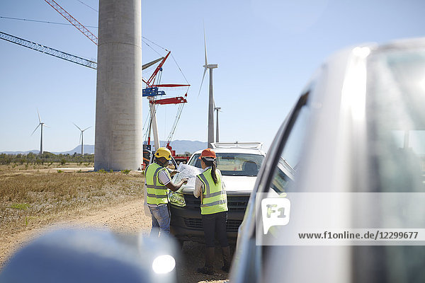 Engineers reviewing blueprints at wind turbine power plant