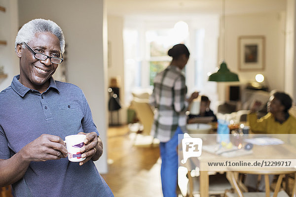 Portrait smiling  confident senior man drinking coffee with family in background