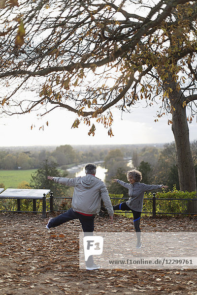 Active senior couple exercising  stretching in autumn park