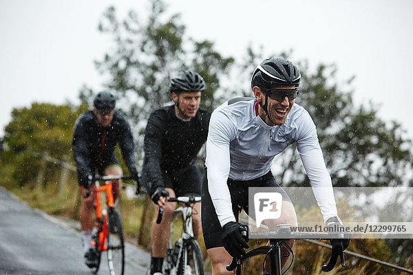 Smiling male cyclist cycling with friends