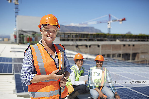 Portrait smiling  confident female engineer with walkie-talkie at sunny solar power plant