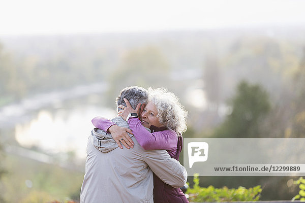 Affectionate active senior couple hugging in nature