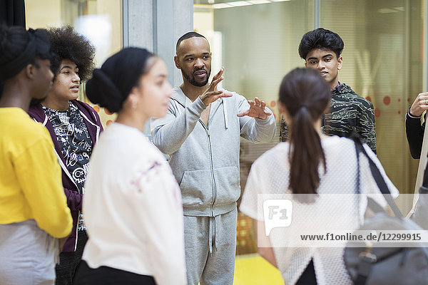 Male instructor leading teenagers in dance class studio