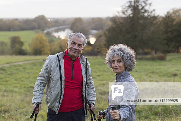 Portrait confident active senior couple hiking in rural field