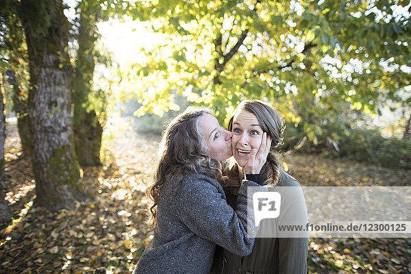 Frau gibt Freund Kuss auf Wange im Park