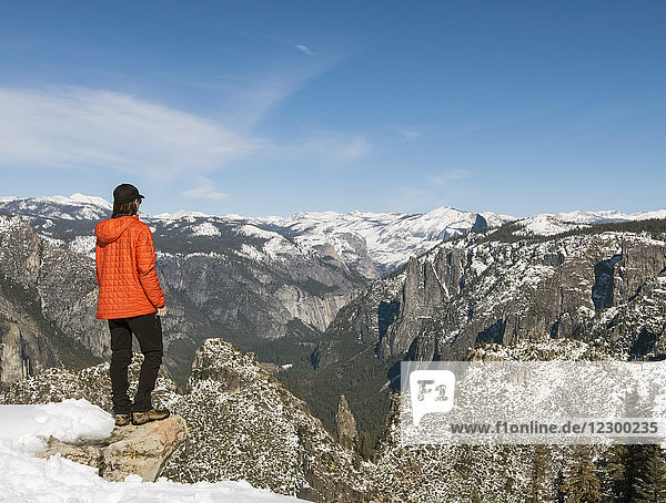 Female hiker looking at view of Yosemite National Park from Taft Point in winter with Half Dome visible  California  USA
