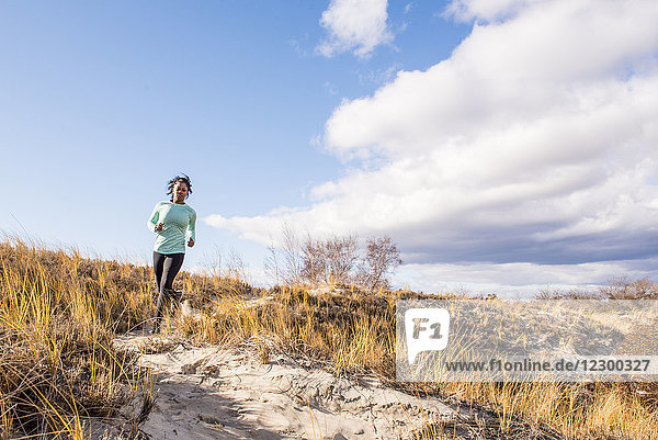 Junge Frau joggt bei sonnigem Wetter auf einem sandigen Weg  Newburyport  Massachusetts  USA
