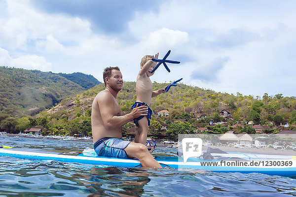 Father and son at sup surfboard Bali Indonesia.