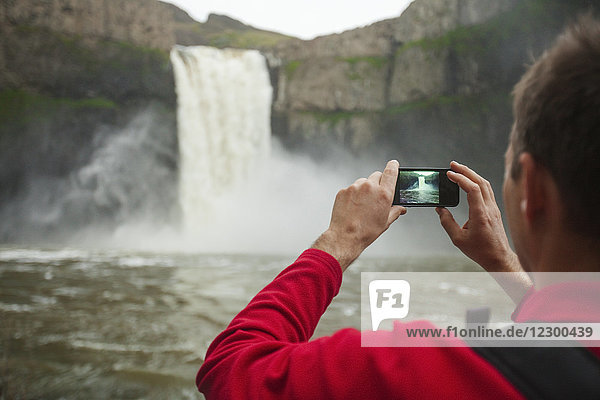 Mann fotografiert den Wasserfall Palouse Falls mit einem Smartphone  Washington State  USA