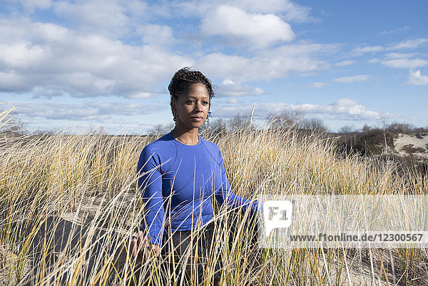 Porträt einer jungen Frau  die auf einer grasbewachsenen Düne meditiert und wegschaut  Newburyport  Massachusetts  USA