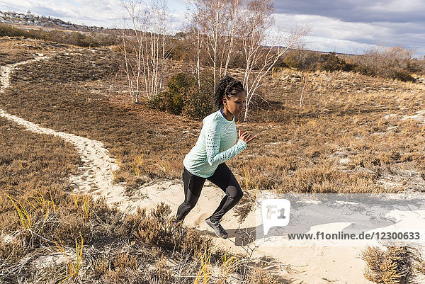 Young woman jogging on narrow sandy path on sunny day  Newburyport  Massachusetts  USA