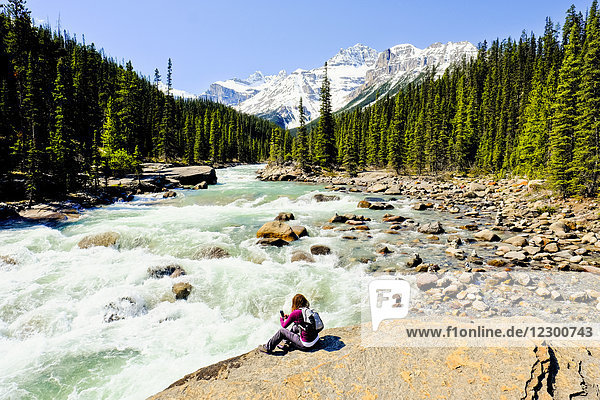 Woman sitting on riverbank at Mistaya Canyon  Banff National Park  Canada