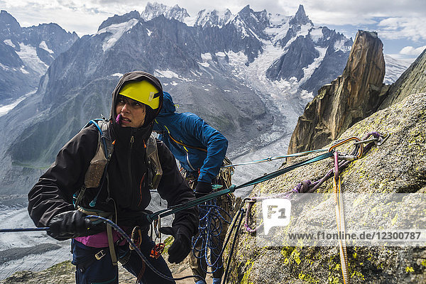 Two adventurous male and female rock climbers rappelling in French Alps  Le Soleil Rendez-Vous avec la Lune on Grepon  Aiguille du Grepon  Haute-Savoie  France
