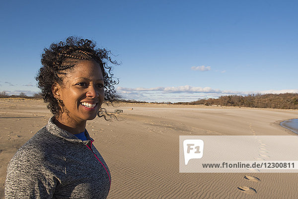 Porträt einer jungen Frau  die am Sandstrand steht und lächelnd wegschaut  Newburyport  Massachusetts  USA