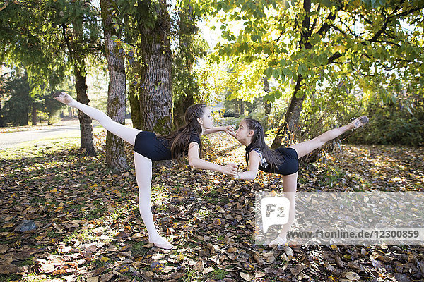 Seitenansicht von zwei Mädchen in Trikots tanzen Ballett im Wald