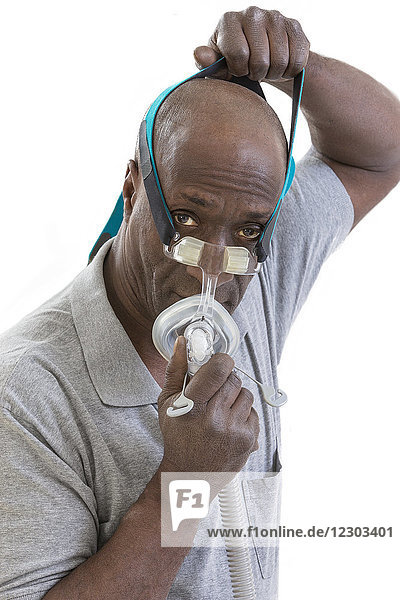 Ein Mann trägt eine CPAP-Maske (Continuous Positive Airway Pressure) zur Behandlung von Schlafapnoe.