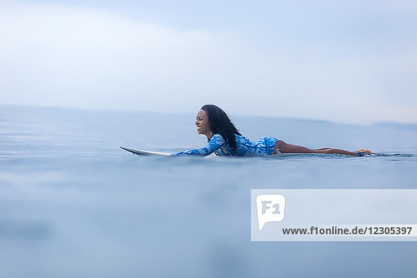 Seitenansicht einer Frau  die auf einem Surfbrett im Meer paddelt