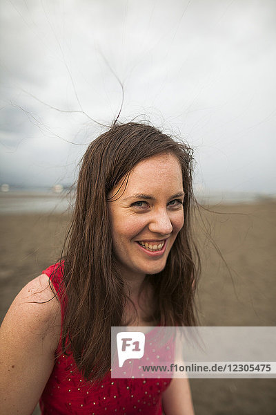 Kopf und Schultern Porträt der lächelnden Frau in rotem Tank-Top am Strand