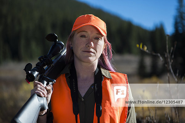 Portrait of female hunter posing with rifle resting over shoulder  Colorado  USA