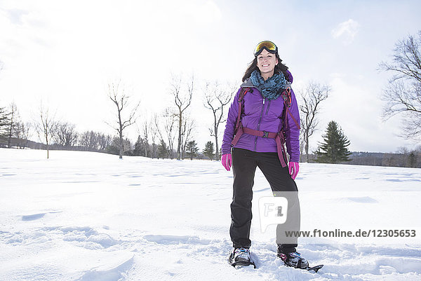 Front view full length shot of woman with snowshoes standing outdoors in winter