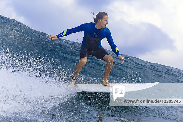 Young man riding wave on surfboard in sea