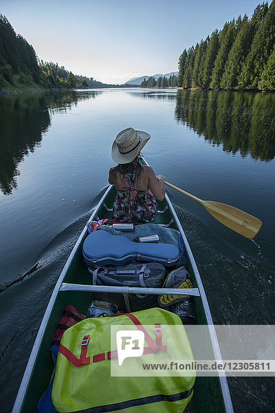 Erwachsene Frau  die mit dem Kanu den Clark Fork River hinunter in den Lake Pend Oreille fährt  um dort zu zelten. Nord-Idaho.