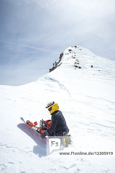 Einsamer abenteuerlustiger Mann  der sein Snowboard zusammenbaut  bevor er im Winter den Berg Shasta hinunterfährt  Kalifornien  USA