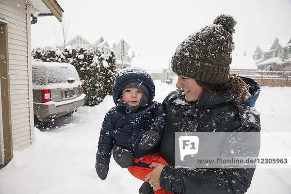 Mother holding baby son outside house in winter
