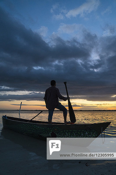 Silhouette of man standing in canoe and holding paddle on seashore  Cancun  Quintana Roo  Mexico