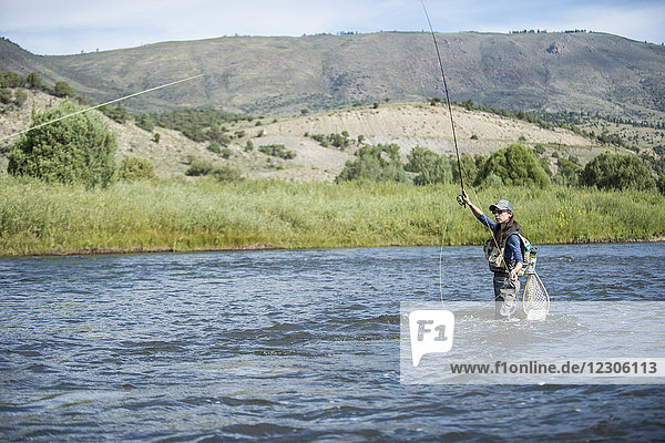 Weiblicher Angler  der an einem sonnigen Tag knietief im Colorado River angelt  Colorado  USA