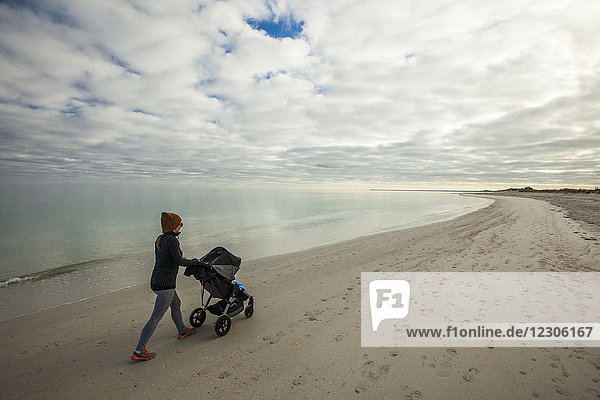 Side view shot of mother with baby stroller at beach of Eagle Bay  Meelup Regional Park  Western Australia