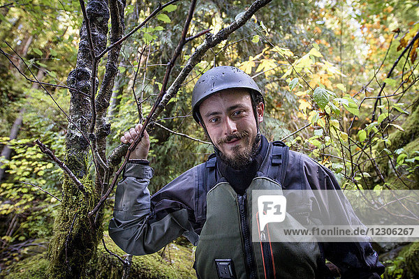 Front view portrait of male whitewater kayaker in forest looking at camera